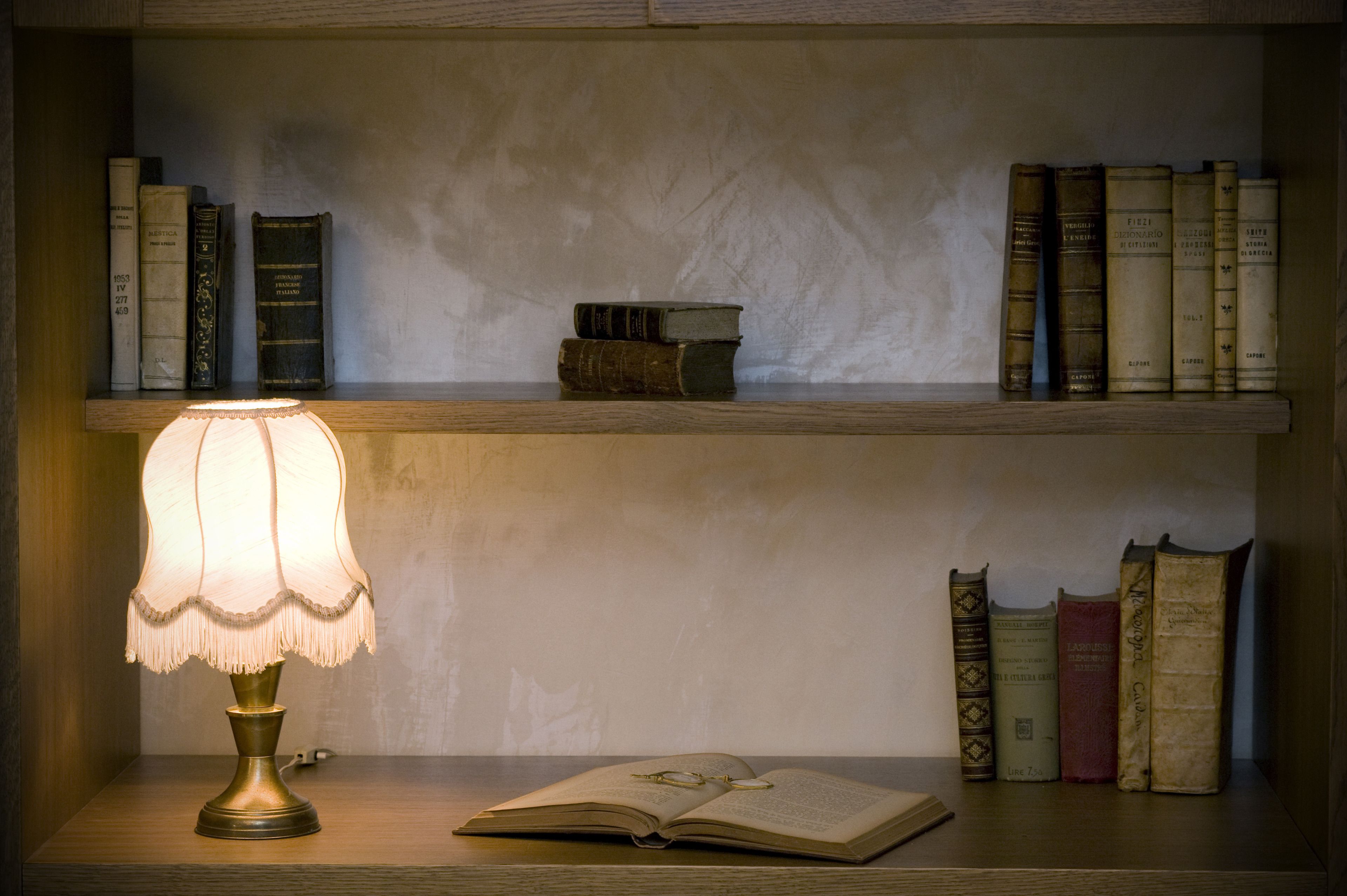 Una mensola di legno con libri e una lampada da tavolo.