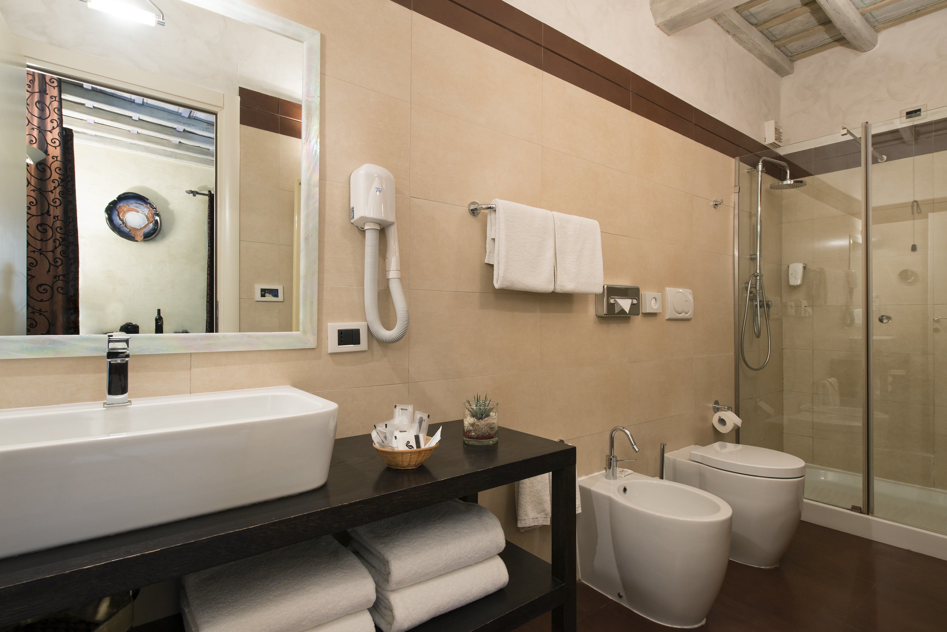 A modern bathroom with a large sink, a glass-enclosed shower, and a toilet.