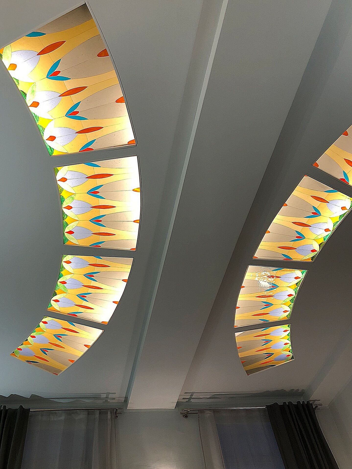A ceiling with multiple stained glass panels featuring a leaf pattern.