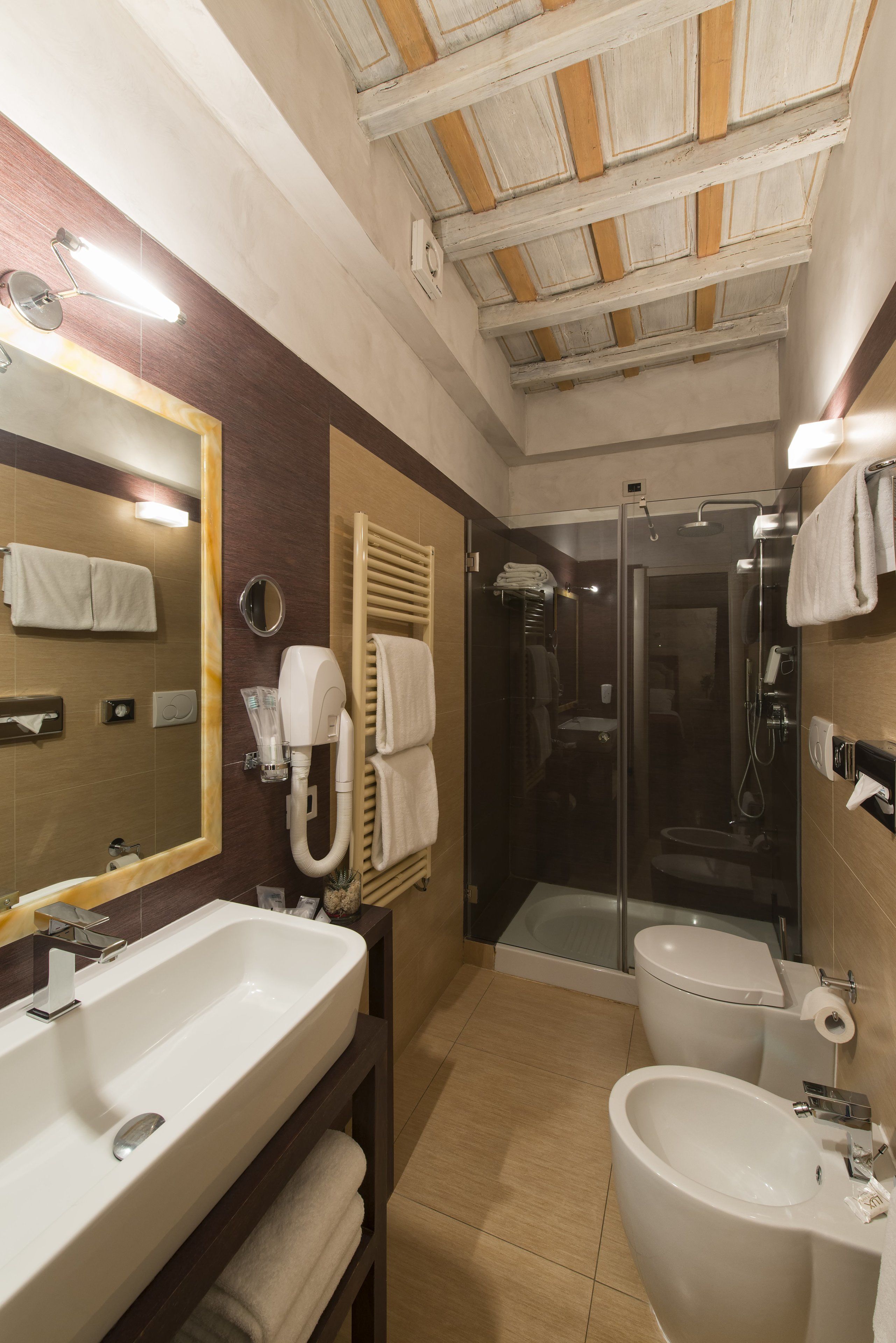 Un baño moderno con un espejo grande, dos lavamanos, una ducha y un inodoro.