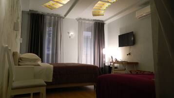 A hotel room with a bed, a desk, a chair, a TV, and a ceiling with skylights.