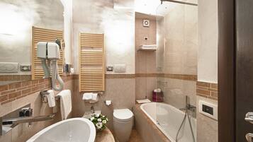 A modern bathroom with a large bathtub, a separate toilet, and a vanity with a sink and mirror.