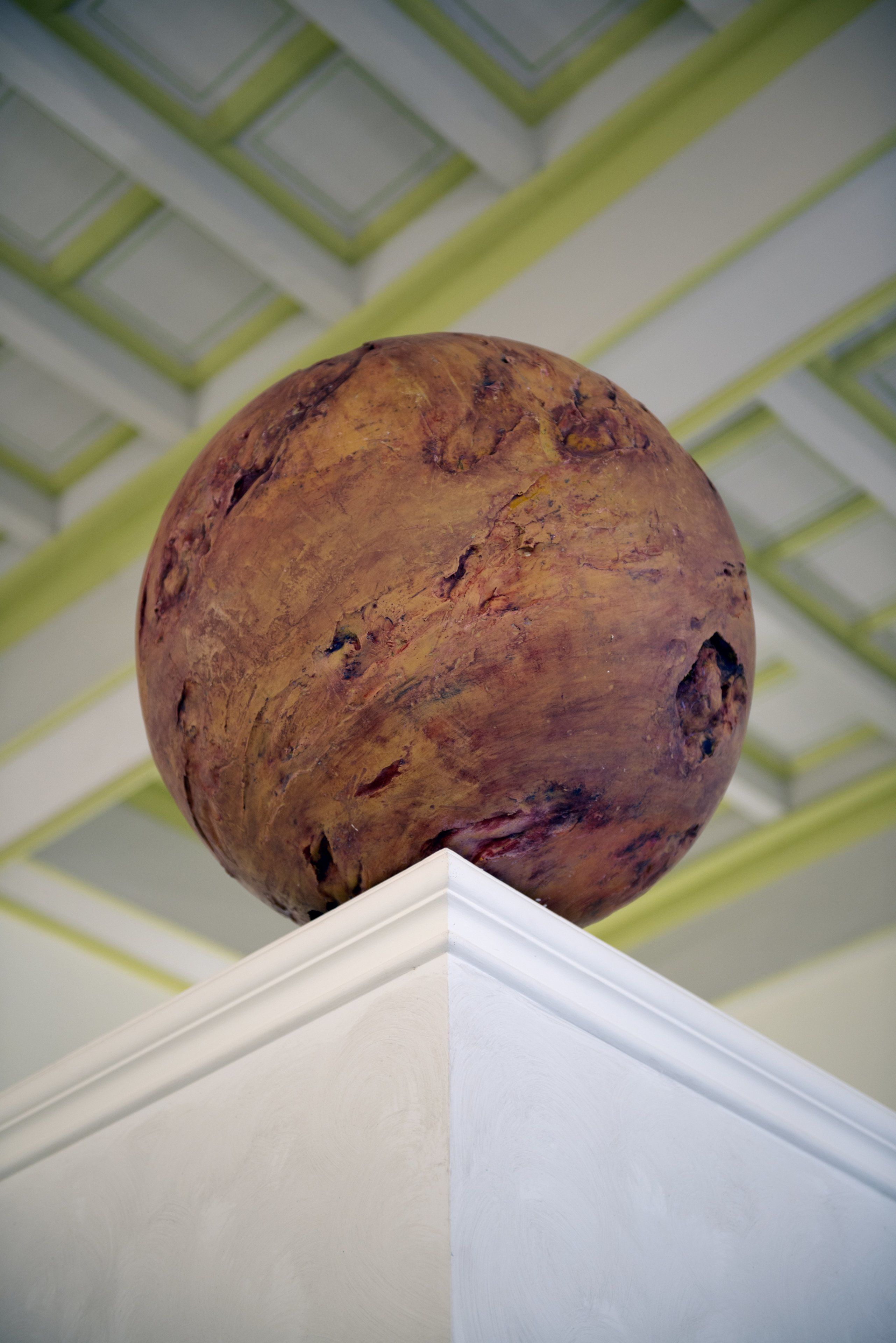 Una gran escultura de madera sobre un pedestal, con un diseño geométrico en el techo.