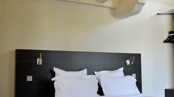 Ett modernt hotellrum med en stor säng, en mörk sänggavel och ett träpanelat tak.
