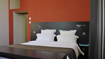 Une chambre d’hôtel moderne avec un grand lit, une tête de lit sombre et un mur d’accent rouge.