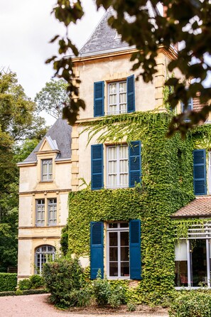 A historic building with a stone facade, blue shutters, and ivy covering the walls. - Chateau De Champlong (Villerest)