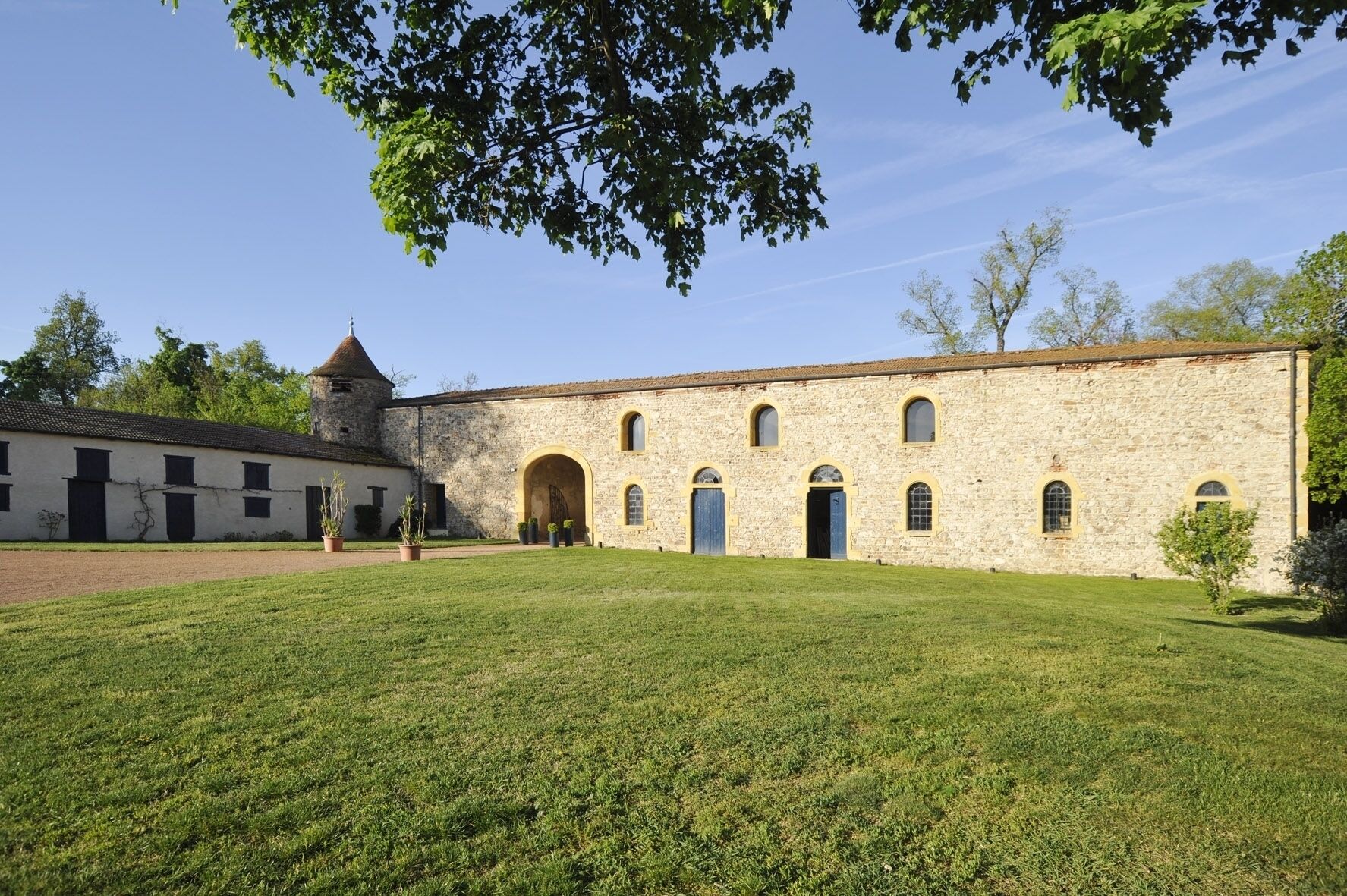 A historic stone building with a central courtyard, arched doorways, and a tower.