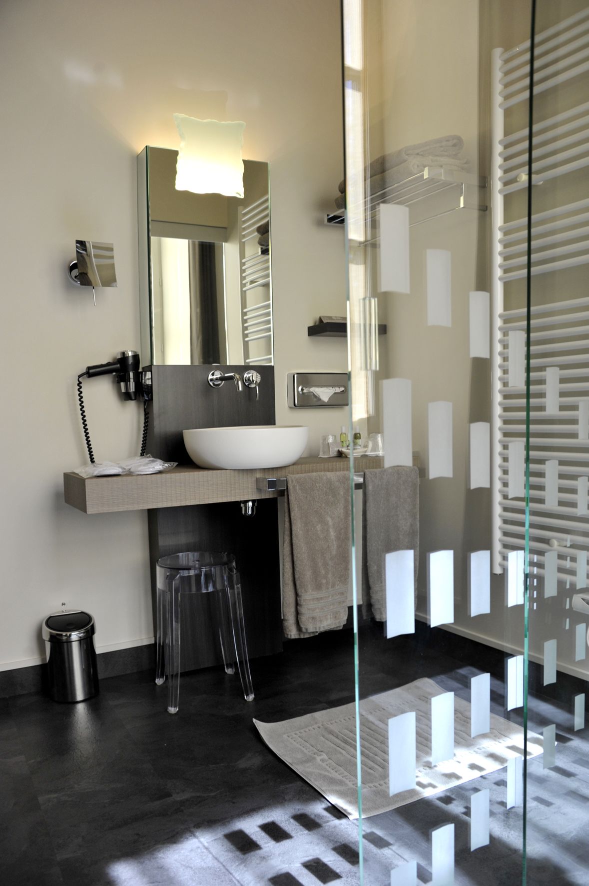 Une salle de bain moderne avec un grand miroir, un lavabo blanc et une cabine de douche en verre.