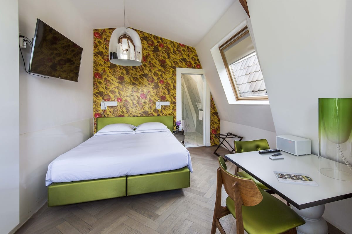 A room with a bed, a desk, a chair, a TV, and a window.