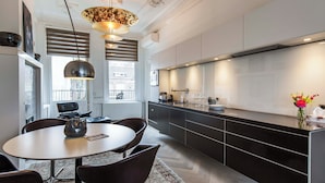 A modern kitchen with a dining area, featuring a round table, chairs, and a pendant light. - Amstel Corner Hotel (Amsterdam)