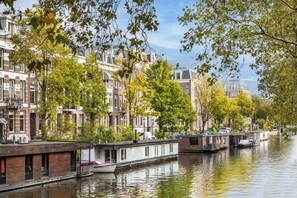 Un bâtiment situé au bord du canal, avec une péniche amarrée devant.