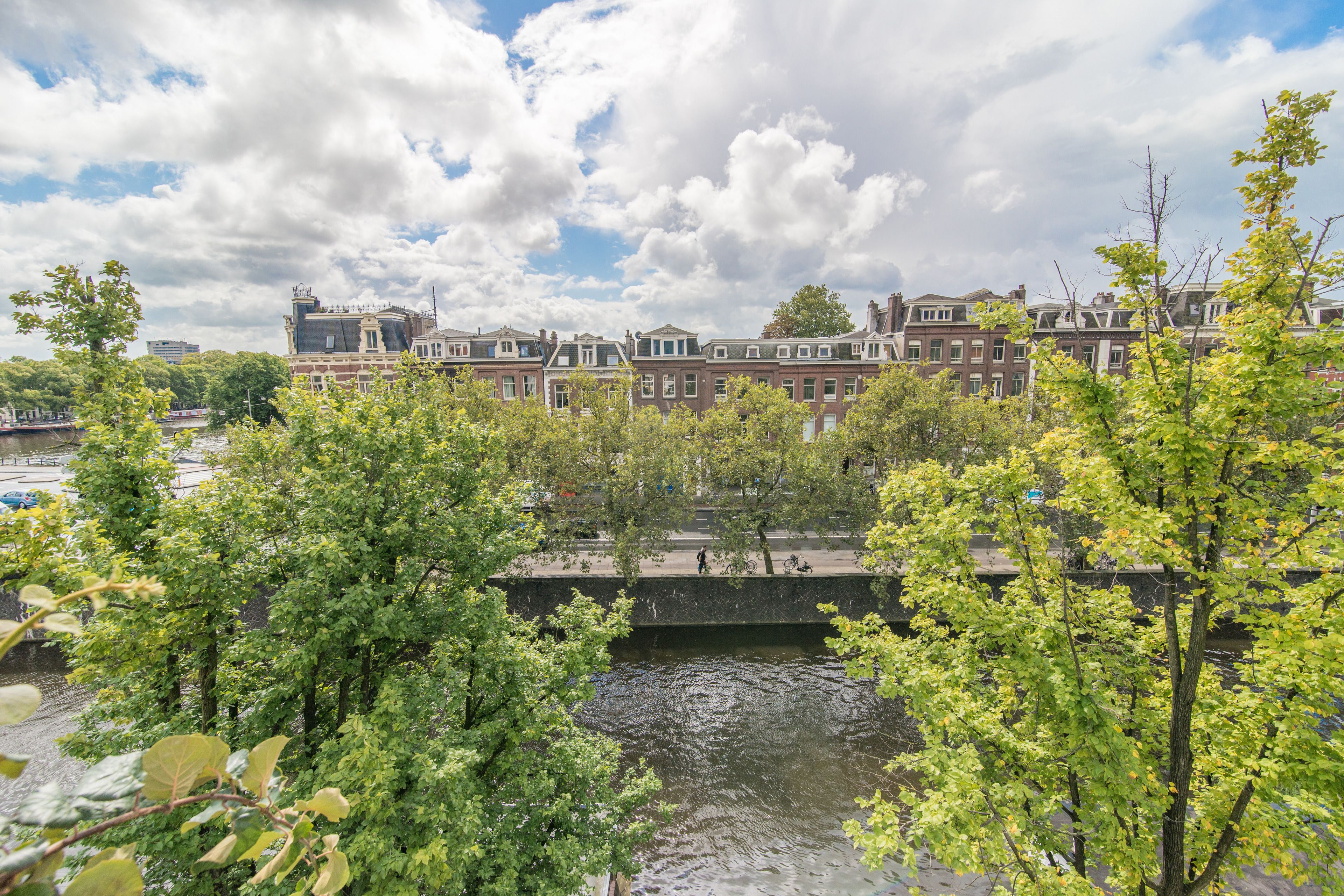 A canal with a bridge, surrounded by trees and historic buildings.