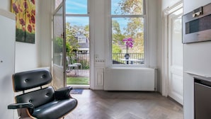 A modern kitchen with a built-in oven, a bench, and a view of the garden through a glass door. - Amstel Corner Hotel (Amsterdam)