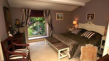 A bedroom with a bed, a chair, a bench, a lamp, and a window with curtains.