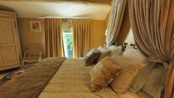 A bedroom with a large bed, curtains, a wooden wardrobe, and a chair.