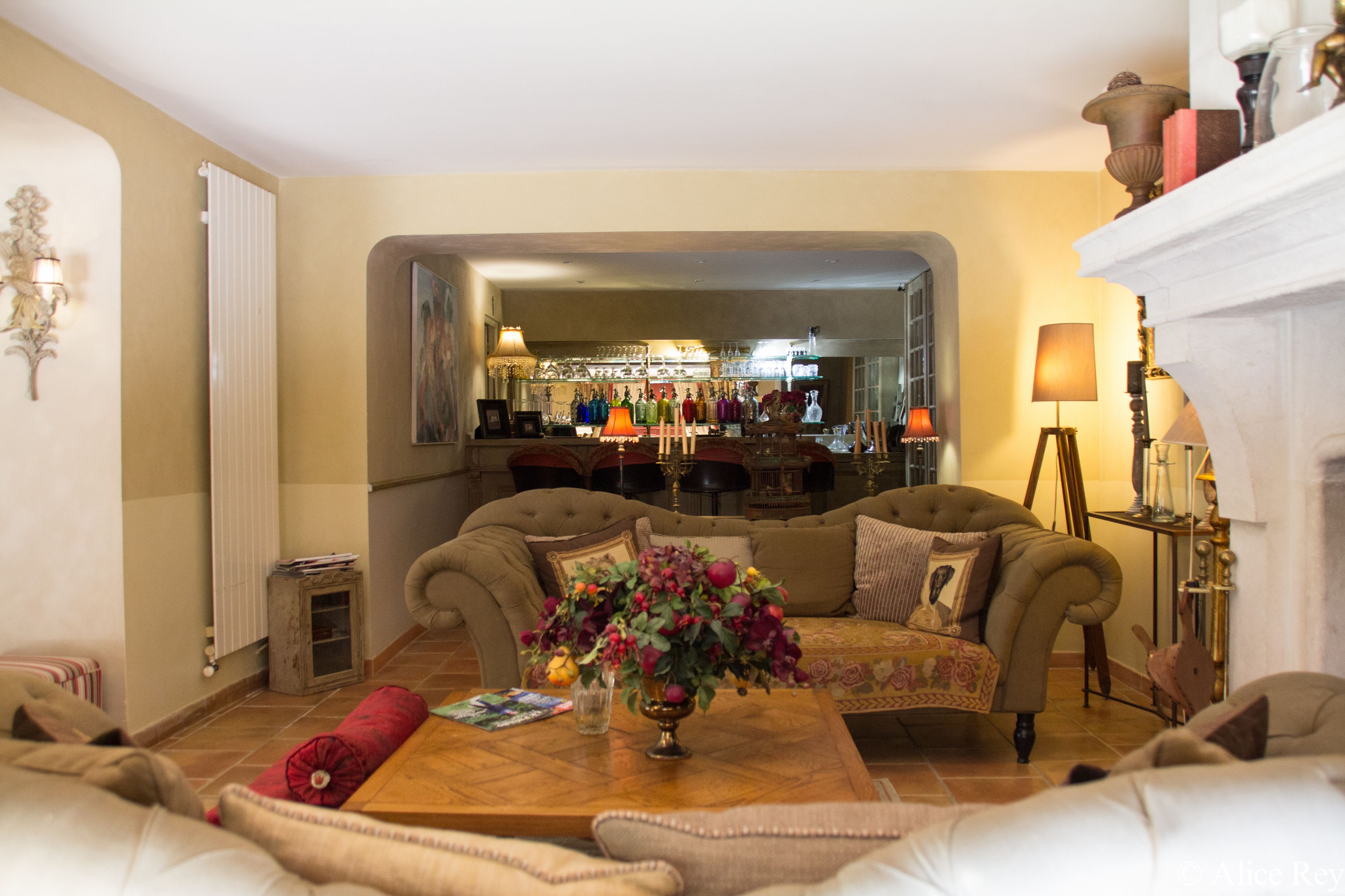Een gezellige woonkamer met een zithoek, een bijzettafeltje met een bloevas en een open haard.