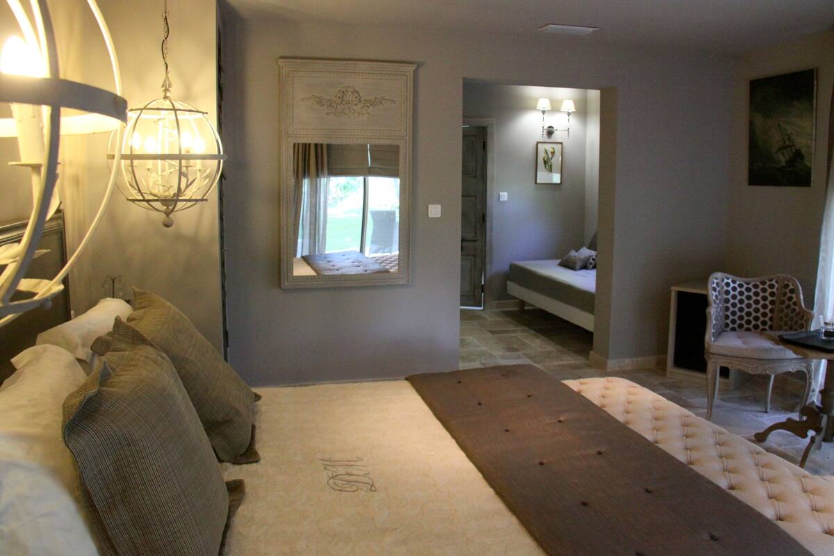 A bedroom with a bed, a wooden bench, a chair, and a lamp.