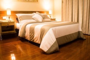 A neatly made bed with a wooden headboard, two bedside lamps, and a telephone on a nightstand. - Charlies Place Hotel & Spa (Bogotá)