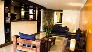 Un hall con muebles de madera, un mostrador de recepción y un jarrón con flores.