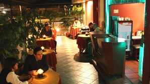 Un restaurante con mesas, sillas, una barra y un refrigerador.