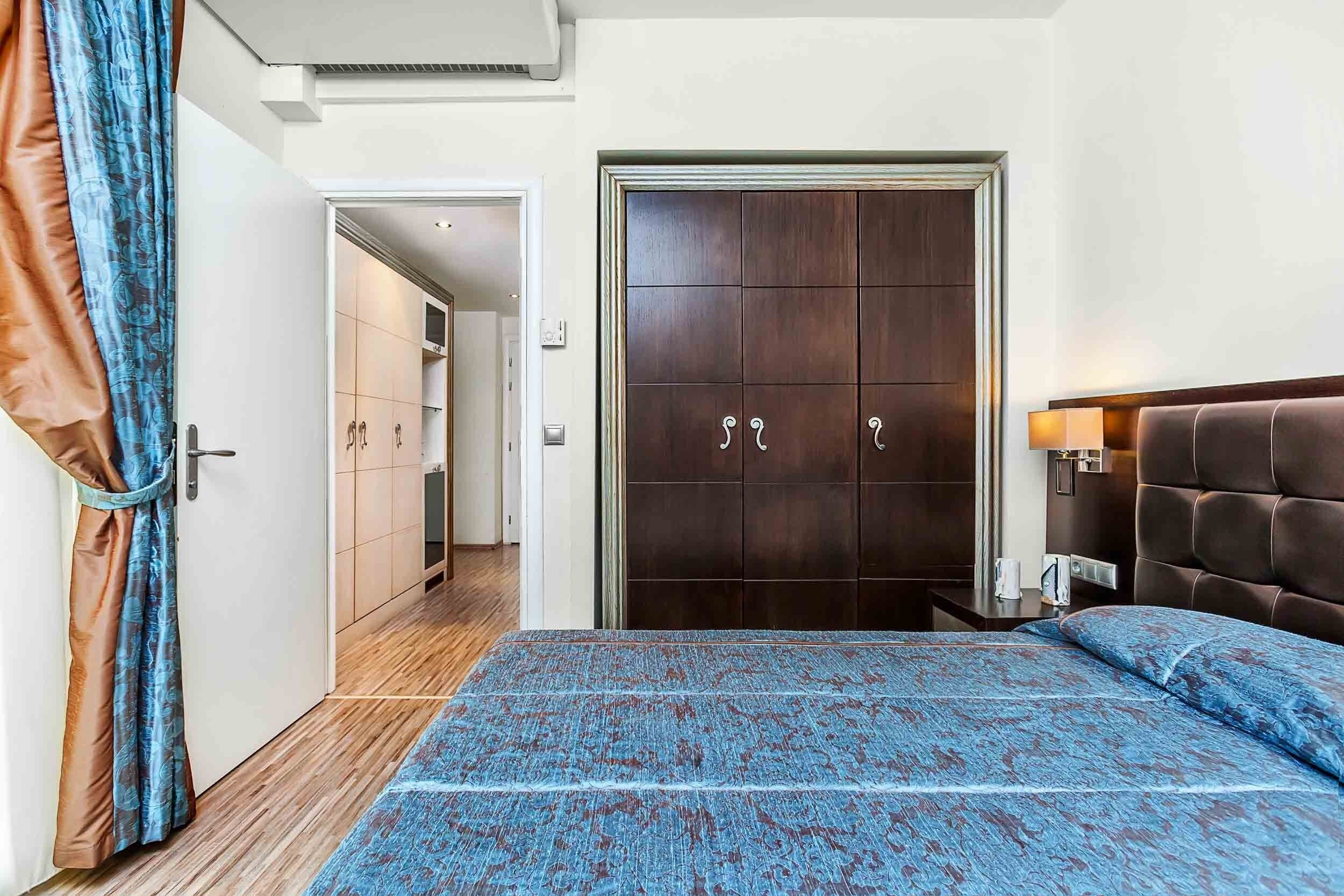 Een slaapkamer met een bed, een kledingkast en een nachtkastje.