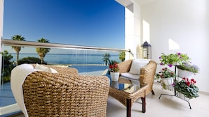 A balcony with wicker furniture, a glass table, and potted plants.
