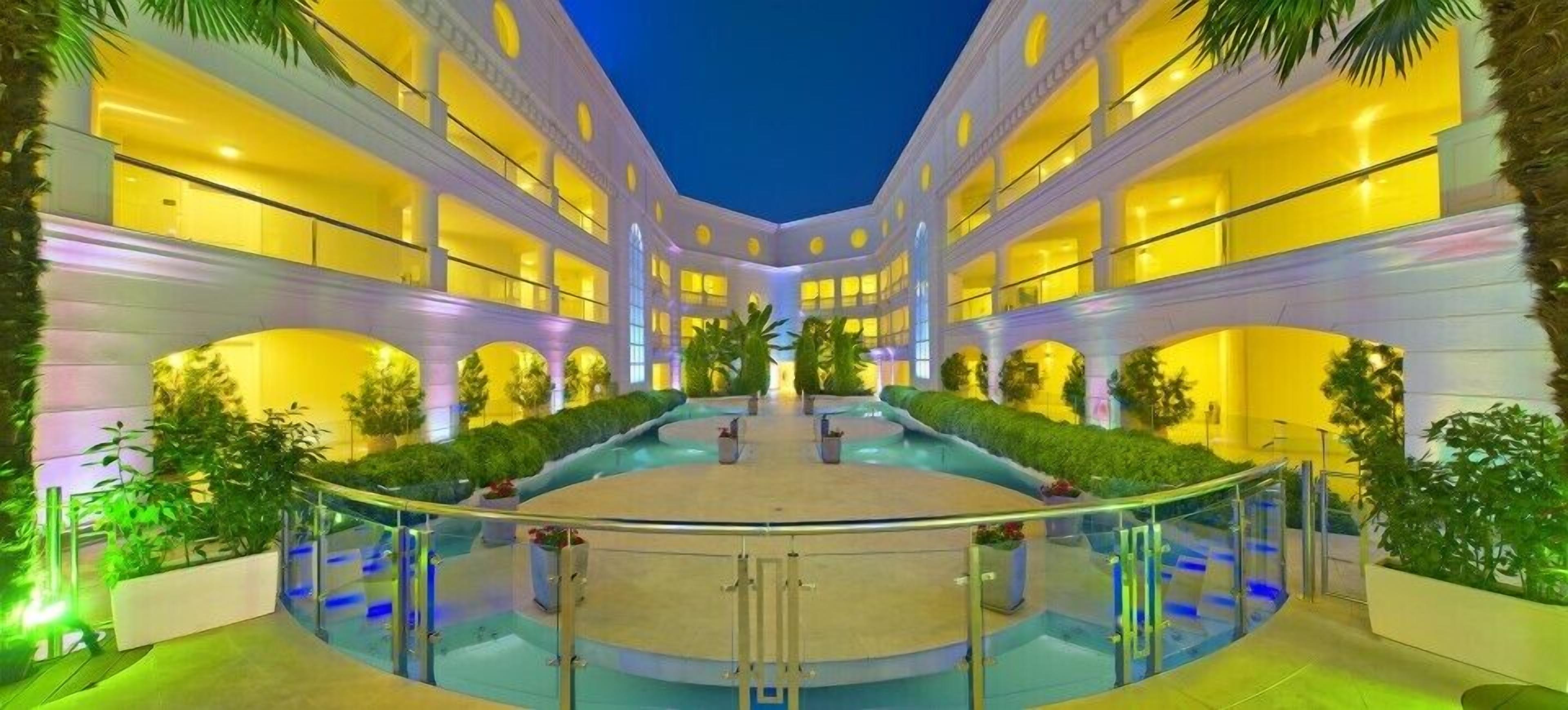 A multi-story hotel with a central courtyard, balconies, and lush greenery.