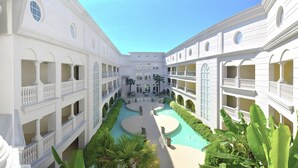 A multi-story hotel with a central courtyard, balconies, and lush greenery.