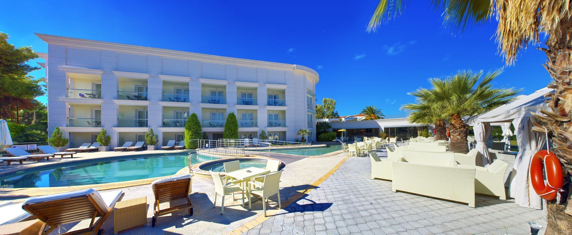A hotel with a pool area, lounge chairs, and a bar.