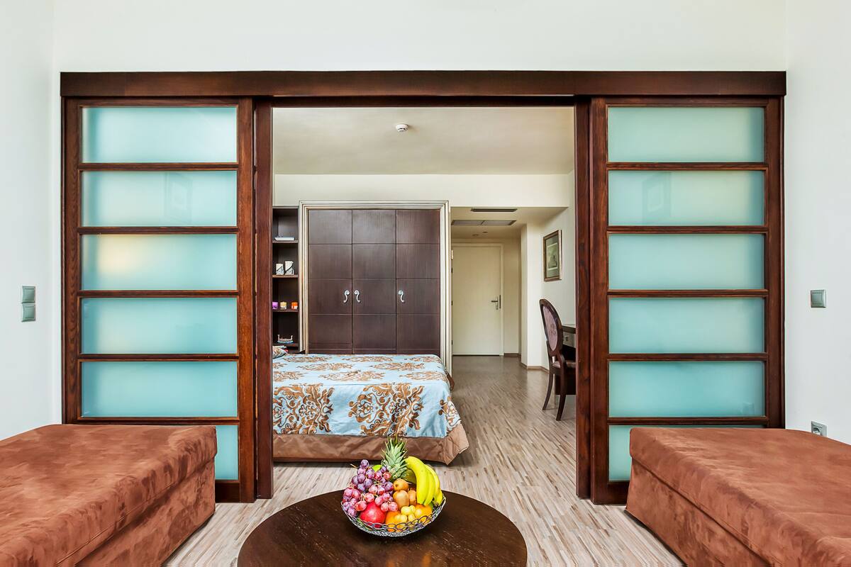 Una habitación con cama, una mesa de comedor con frutero y vista a un pasillo con armario.