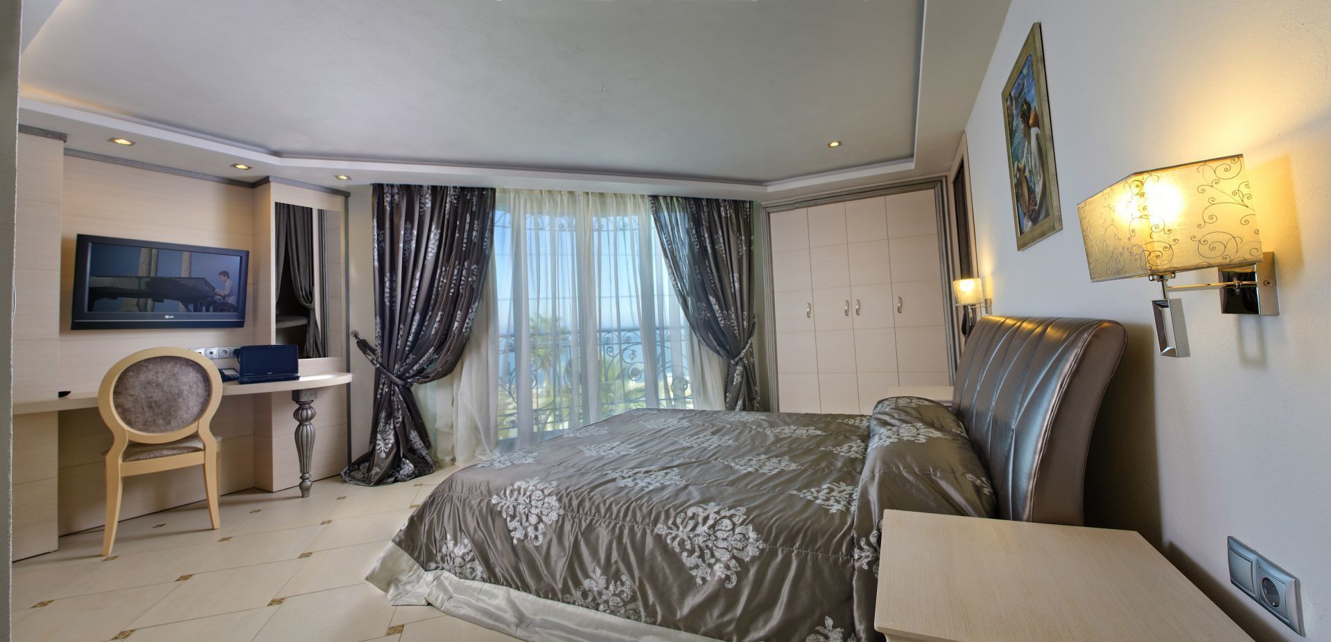 Una camera d'albergo con un letto, una scrivania, una sedia, una televisione e una finestra con tende.