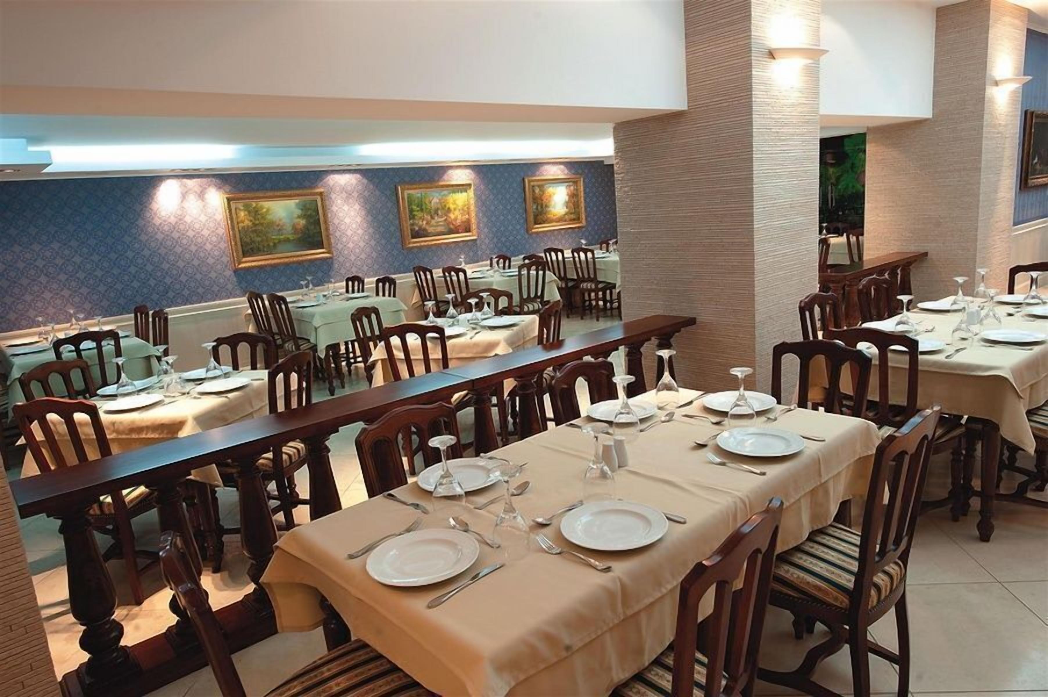 Un espace repas avec de longues tables disposées pour accueillir plusieurs convives, agrémenté de chaises en bois et d’une palette de couleurs neutres.