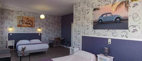 A hotel room with two beds, a desk, a chair, and a small table.