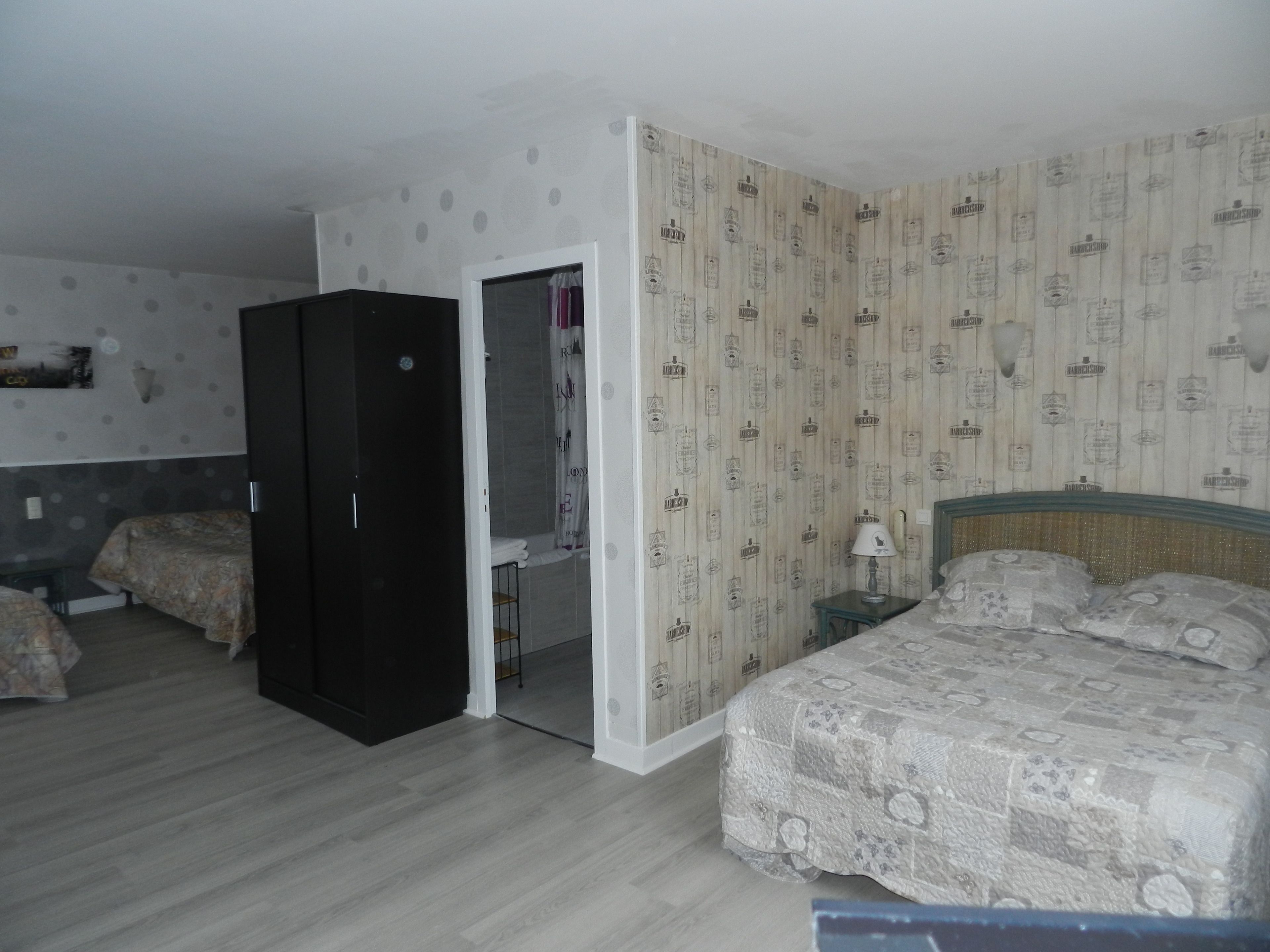 A bedroom with a bed, two bedside tables, a wardrobe, and a bathroom with a shower curtain.