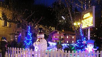 A snowman and a snowman figure in front of a house with a lit signboard.