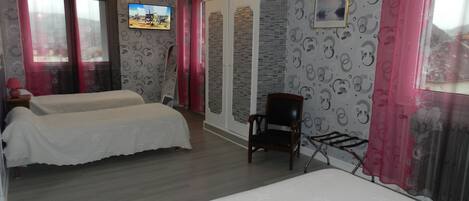 Une chambre avec deux lits, une chaise, un téléviseur et une armoire.