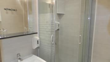 Een moderne badkamer met een douchekabinet van glas, een witte wastafel en een spiegel boven de wastafel.