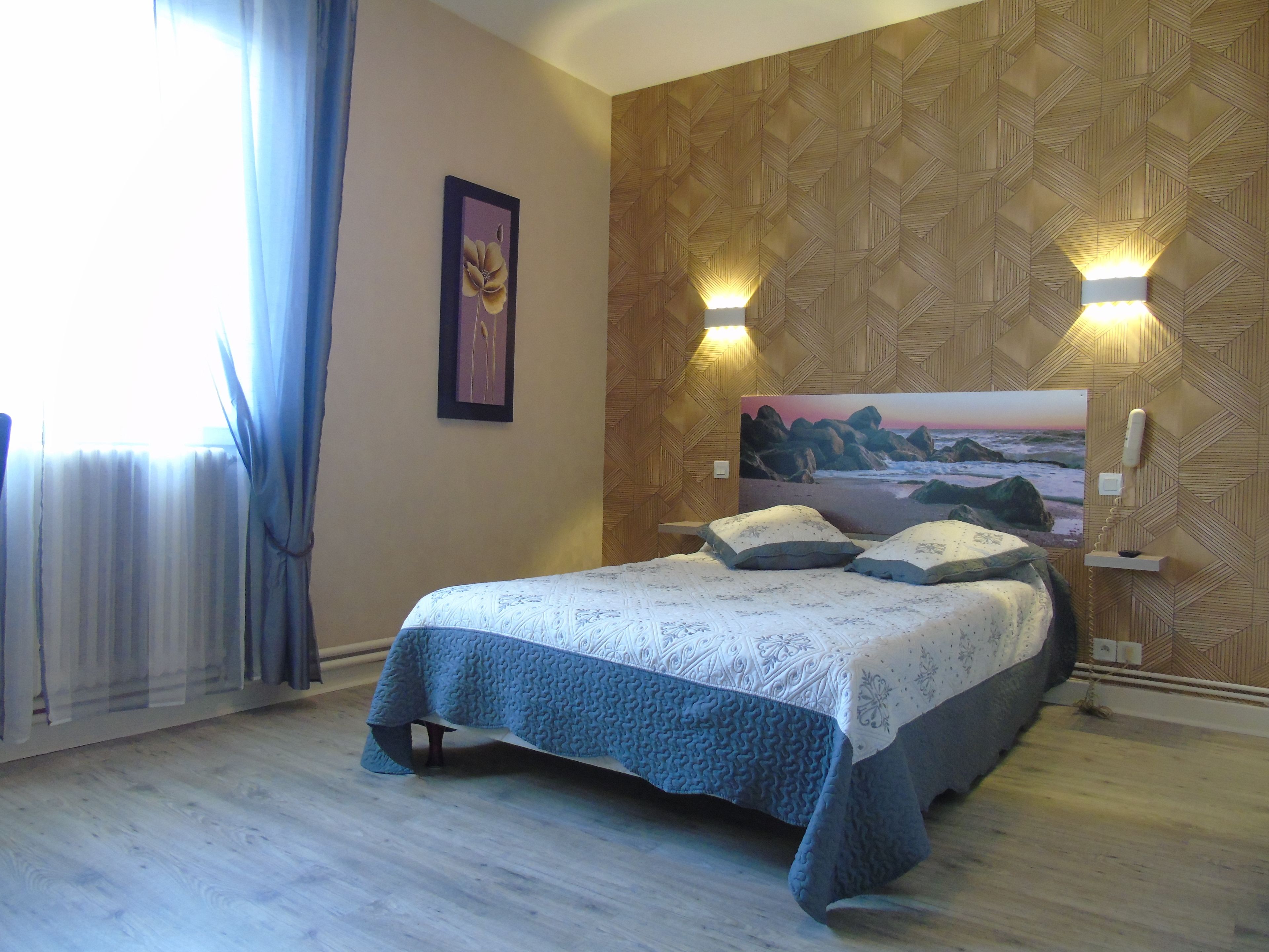 A bedroom with a bed, a framed picture on the wall, and two wall-mounted lights.