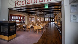 Un restaurante con techo alto, vigas de madera y una amplia zona de comedor con mesas y sillas.