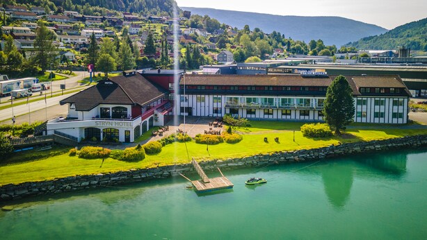Un hotel con piscina, muelle y vistas del pueblo y las montañas circundantes.