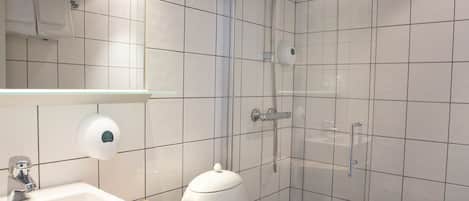 Een moderne badkamer met een wit wastafelmeubel, toilet en douche.
