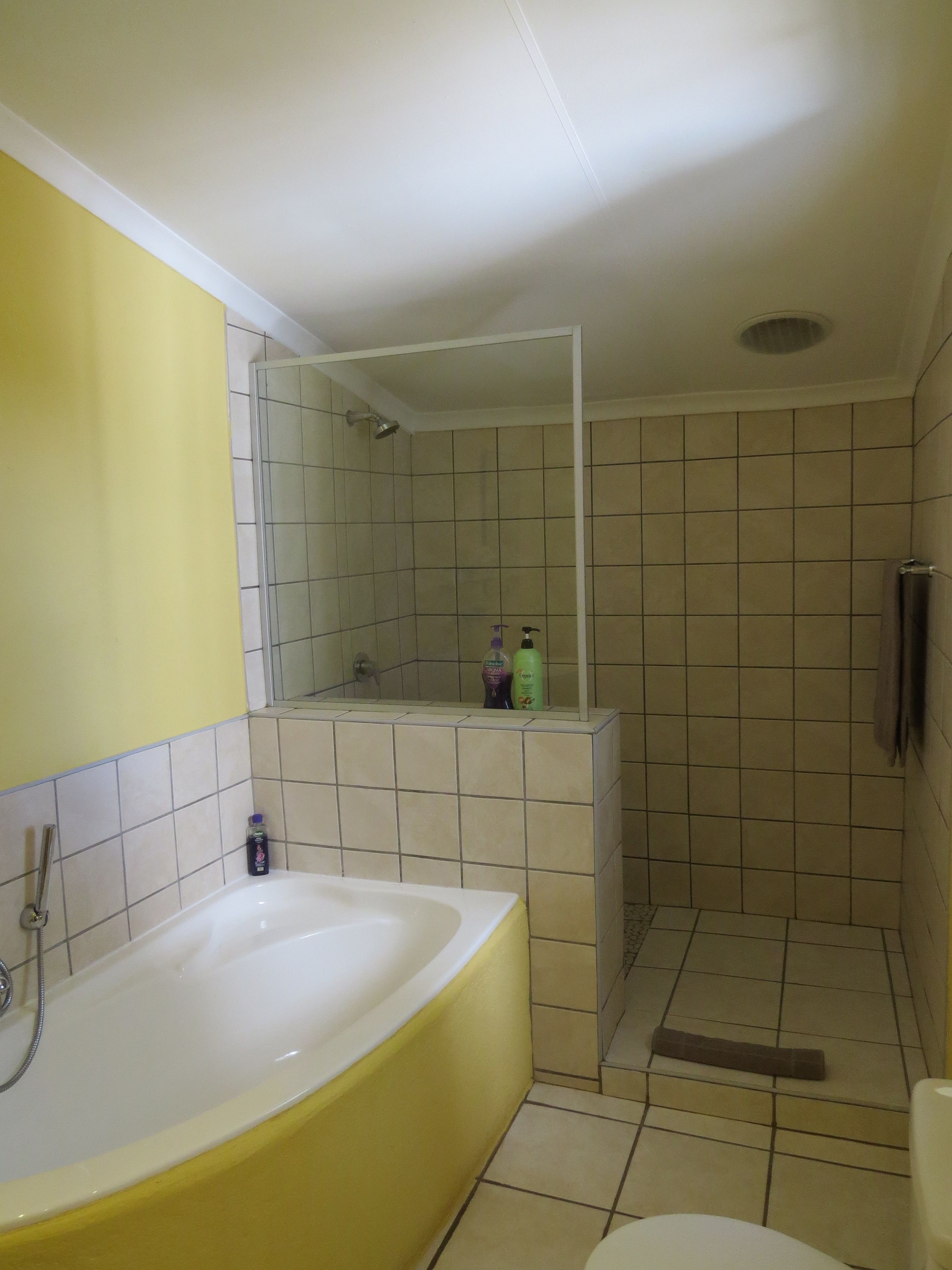 A bathroom with a bathtub, a toilet, and a shower area.
