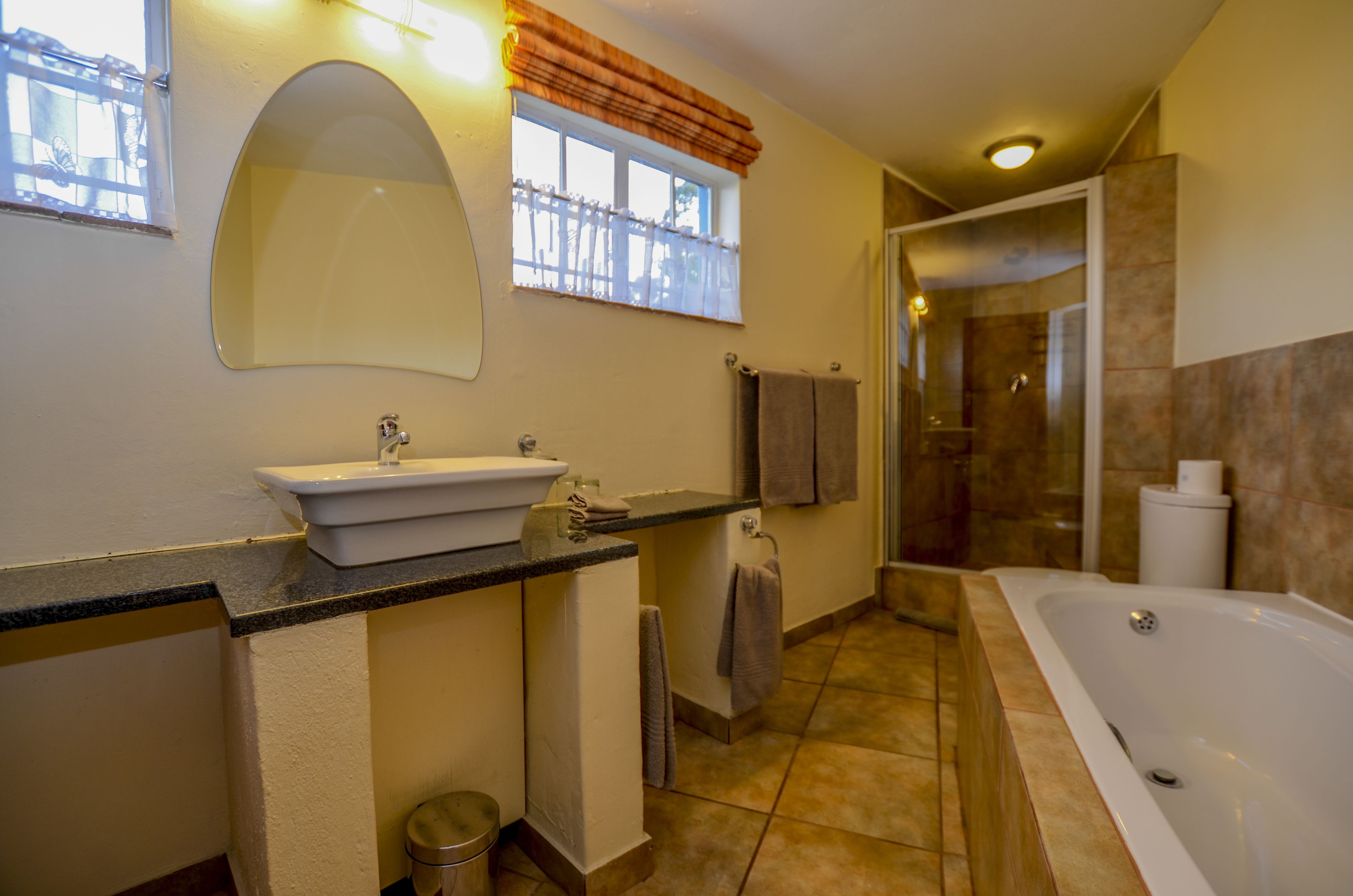 Een badkamer met een wastafel, spiegel, handdoekrek en een bad.