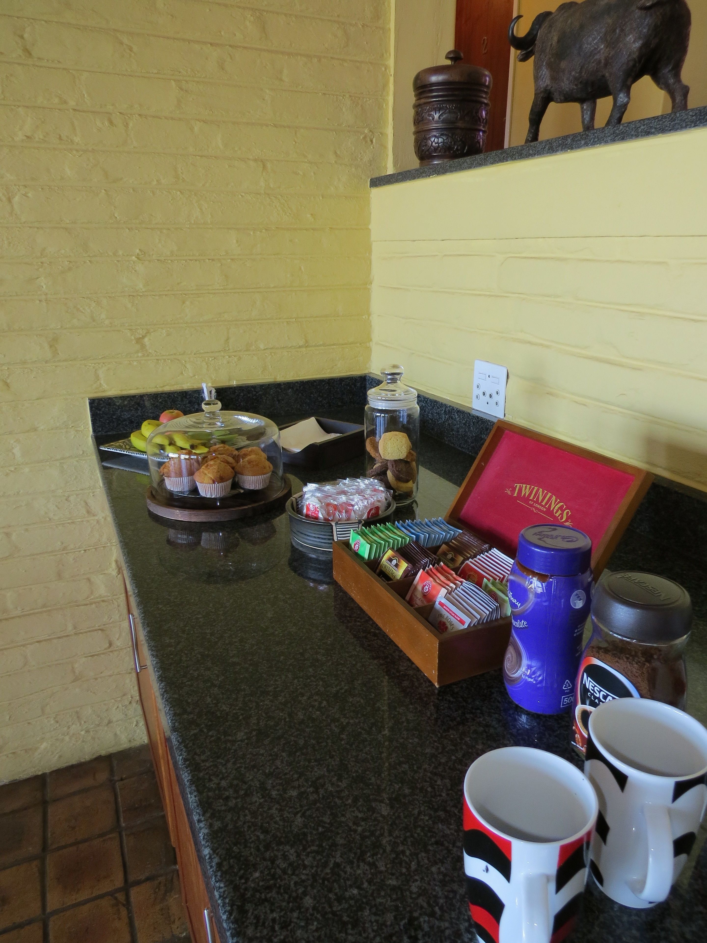 Una barra de desayuno con una variedad de pasteles, muffins y una caja de té Twinings.