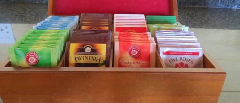 Una caja de madera con compartimentos que contienen varias bolsitas de té etiquetadas como 'Twinings of London'.