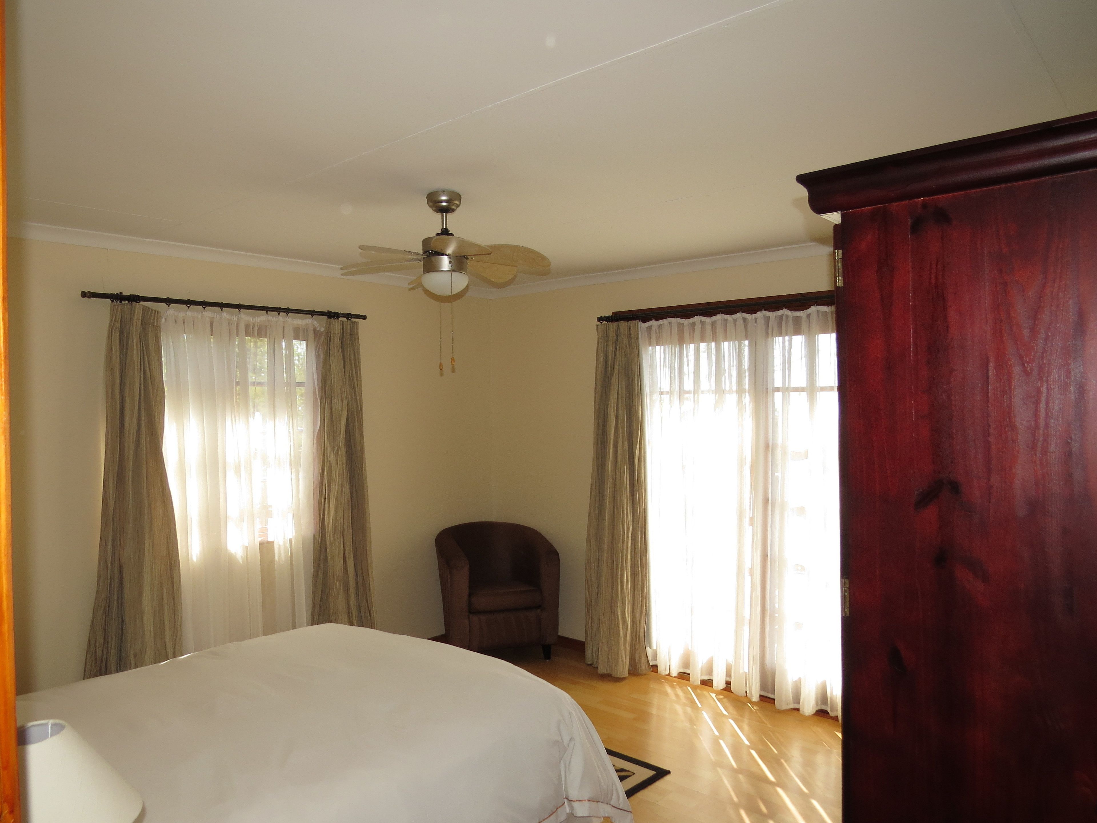 Quarto com cama, ventoinha no teto e cortinas.