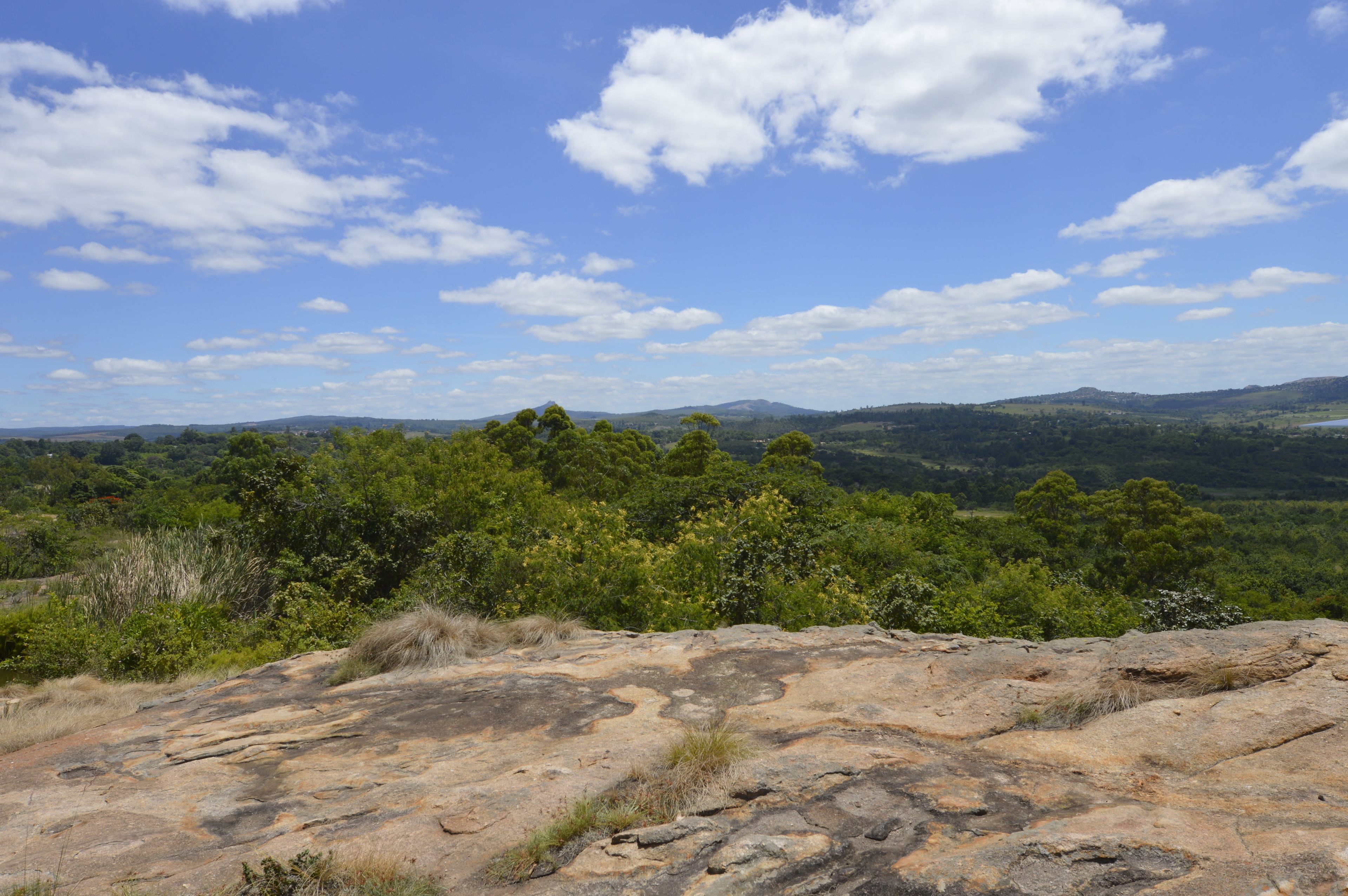 A rocky landscape with a view of distant hills and a clear sky.