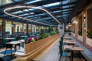A modern indoor dining area with a curved counter, green chairs, and pendant lighting. - Andelapartments (Prague)