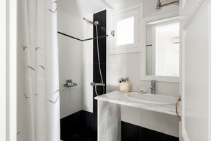 A modern bathroom with a shower, a sink, and a mirror. - Casa Bianca (Santorini)