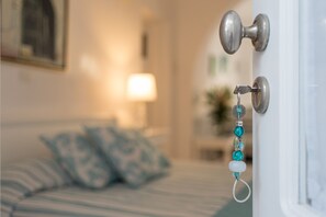 A bedroom with a bed, pillows, and a door with a keychain. - Casa Bianca (Santorini)